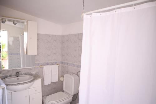 a bathroom with a toilet and a sink and a shower curtain at Salema Beach Private Villa in Salema
