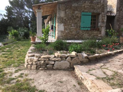 une maison avec un mur en pierre devant une cour dans l'établissement Mas de la Pinède ex-Les Arbousiers, à Bollène