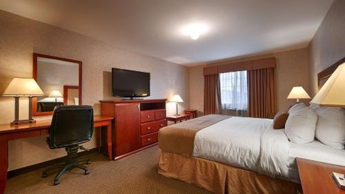 a hotel room with a bed and a desk and a television at Best Western Gold Rush Inn in Whitehorse