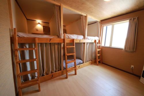 a room with two bunk beds and a window at Guest House Nemuroman in Nemuro