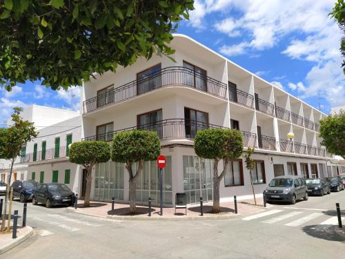 un bâtiment blanc avec des voitures garées devant lui dans l'établissement Hostal Residencia Nicolau, à Sant Antoni de Portmany