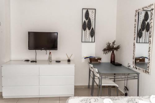 sala de estar con escritorio y TV en una pared blanca en סטודיו ליה - studio lia eilat, en Eilat