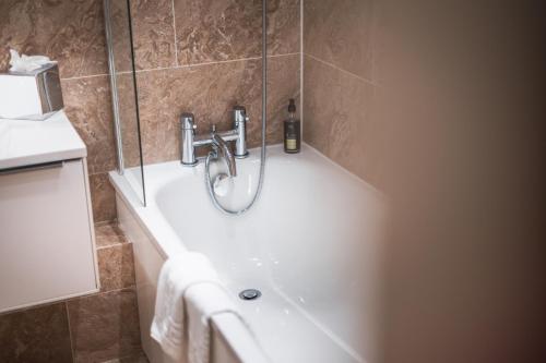 a bathroom with a bath tub with a faucet at No1 The Mansions By Mansley in London