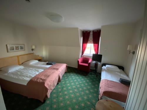 a hotel room with two beds and a red chair at Broby Gästgivaregård in Sunne
