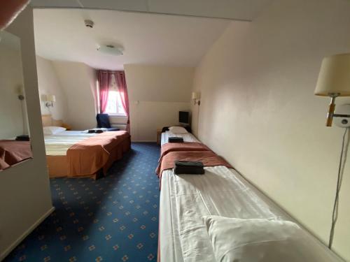a hotel room with two beds and a window at Broby Gästgivaregård in Sunne