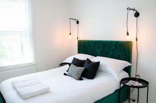 a bed with a green headboard and two pillows at Boutique Getaway, edge of Old Town- 4min walk to beach in Margate