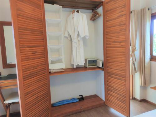 a closet with wooden doors and a white robe at Armonia Village Resort and Spa in Chumphon