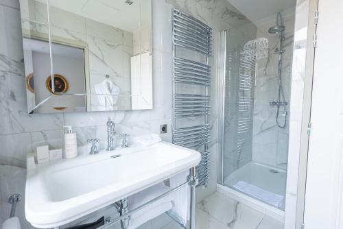 a white bathroom with a sink and a shower at Hôtel Mille Pas in Voiron