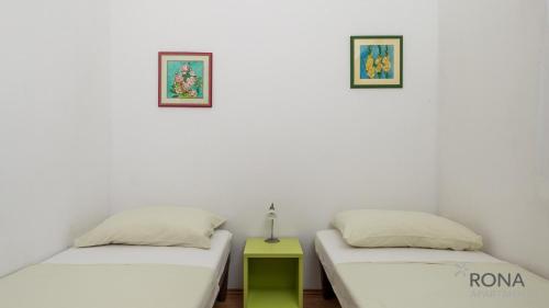 two beds in a room with two pictures on the wall at Rona Apartment Zdravko in Barbariga