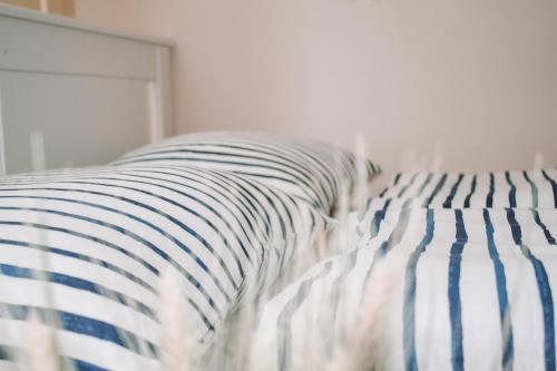 ein Bett mit blau-weißer gestreifter Bettwäsche und einem Kissen in der Unterkunft NEB-THUN LODGE`s Appartement 1 Hilterfingen Ringstrasse 6 in Thun