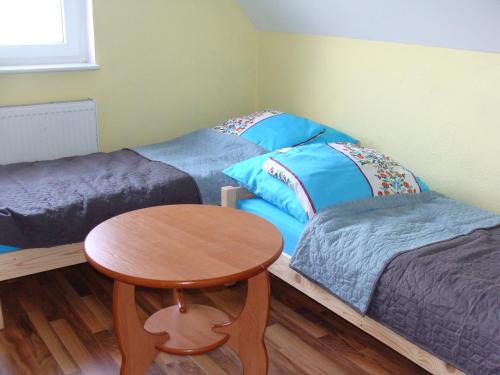 a bedroom with two beds and a wooden table at Berneński Zakątek in Charzykowy