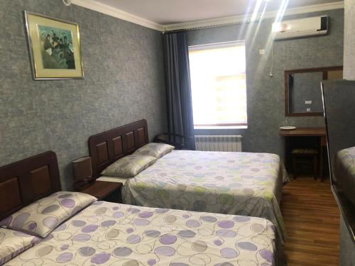 a hotel room with two beds and a window at Cinzano Complex in Samarkand
