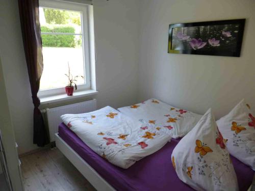 een slaapkamer met een bed met kussens en een raam bij Ambiente in Westerholz