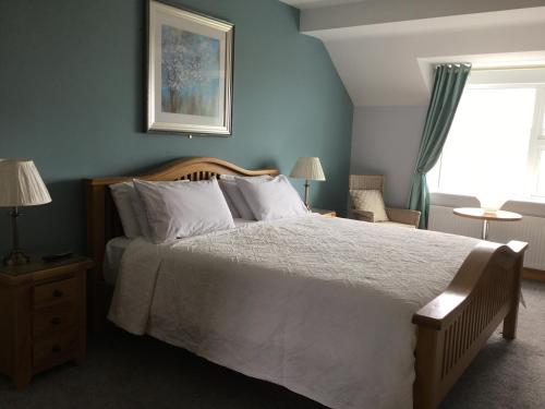 a bedroom with a bed with white sheets and a window at Atlantic View House in Doolin