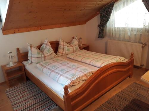 ein Schlafzimmer mit einem Holzbett mit Kissen in der Unterkunft Ferienwohnungen Eggarter in Fresach