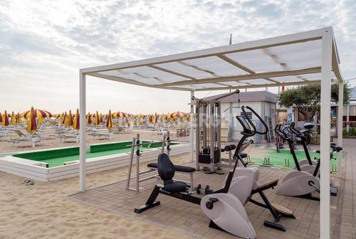 a gym with exercise equipment in front of a pool at Hotel Paradiso in Rimini