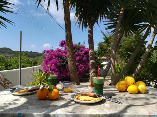 einen Tisch mit Teller mit Lebensmitteln und Obst darauf in der Unterkunft Lemon Tree Cottage in Finikounda