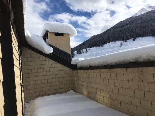 a snow covered roof of a house with a snow covered ground at Ferienhaus Somareiva in Savognin