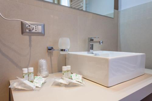 La salle de bains est pourvue d'un lavabo blanc et d'un miroir. dans l'établissement Five Rooms Brolo, à Brolo