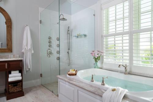 a white bathroom with a tub and a shower at Port d'Hiver Bed and Breakfast in Melbourne Beach