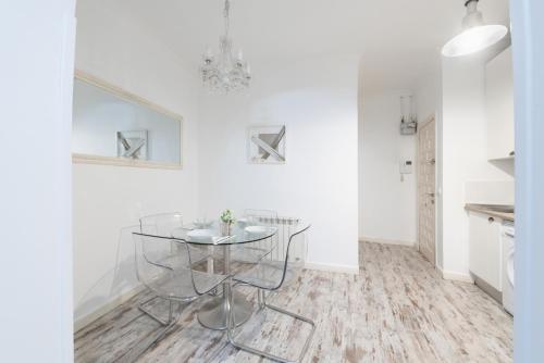 uma sala de jantar com uma mesa de vidro e paredes brancas em Apartamentos Day Madrid PLAZA DE ESPAÑA Centro Gran Via Sol Malasaña em Madri