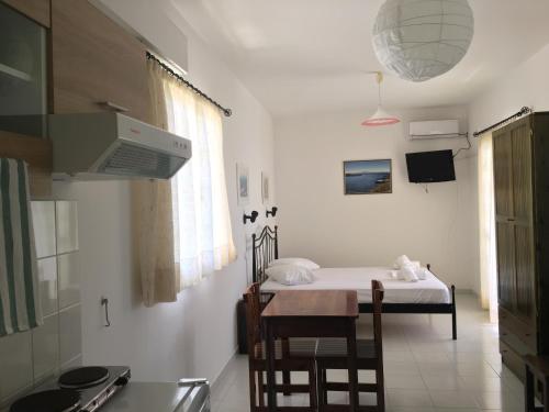 Zimmer mit einem Bett und einem Tisch sowie einer Küche in der Unterkunft Camelia Studios in Yénion
