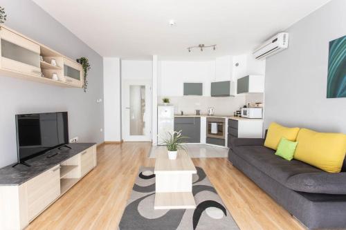 ein Wohnzimmer mit einem Sofa und einem TV in der Unterkunft Corvin Plaza Apartments & Suites in Budapest