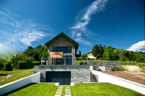 een huis aan de zijkant van een heuvel met gras bij Panorama & Vino Szigliget in Szigliget