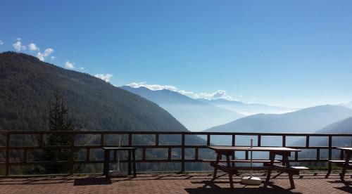 a picnic table on a balcony with a view of mountains at Belvedere Mountain Experience in Monno