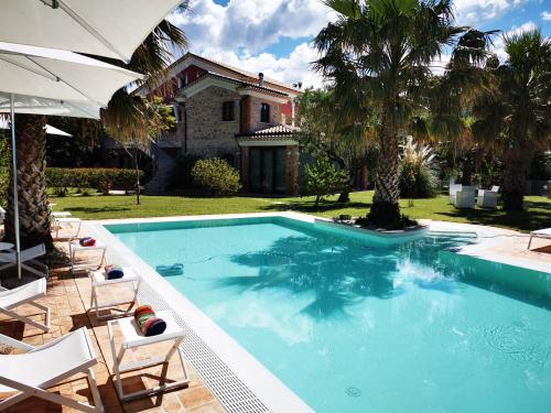 a swimming pool with chairs and a house at Il Mandorlo in Amantea
