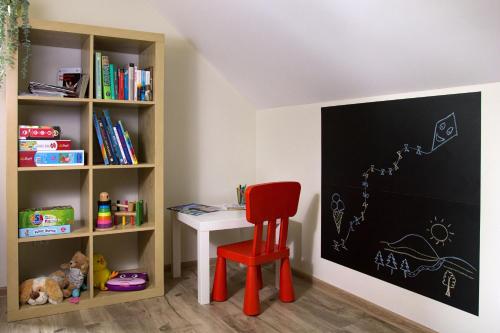 a desk with a red chair next to a book shelf at Barwald Hills - jacuzzi i piękny widok na Babią Górę i Beskidy in Wadowice