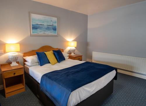 a bedroom with a large bed with blue and yellow pillows at Murphy's Hotel in Tobercurry