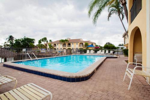 OYO Waterfront Hotel- Cape Coral Fort Myers, FL في كيب كورال: مسبح في منتجع فيه كراسي و نخلة
