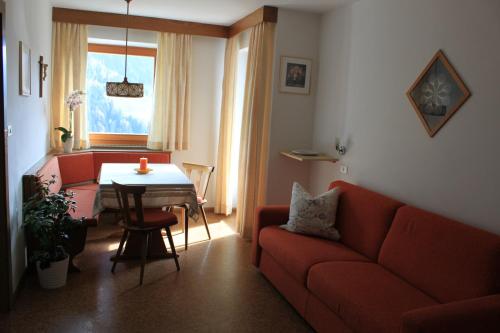 a living room with a red couch and a table at Haus Tasser in San Lorenzo di Sebato