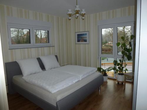 uma cama num quarto com duas janelas em Ferienoase an der Wublitz em Potsdam