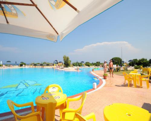 een zwembad met gele tafels en stoelen bij Villetta La Ginestra in Stintino