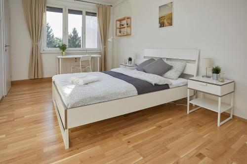 a bedroom with a large white bed and a wooden floor at Gemütliches Apartment in zentraler Lage in Graz