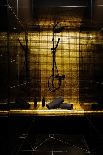 a shower in a bathroom with a yellow tile wall at Apartments in Kaunas city centre with Jacuzzi bath in Kaunas