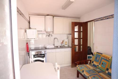 a kitchen with white cabinets and a table and chairs at Salema Beach Private Villa in Salema