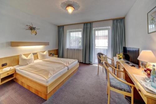 ein Hotelzimmer mit einem Bett und einem Schreibtisch in der Unterkunft Ferienhotel Kollmerhof in Rimbach