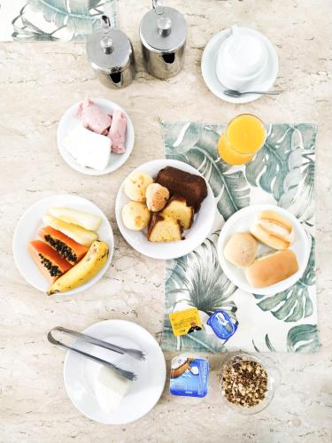 a table topped with plates of food and orange juice at Savassi Village in Belo Horizonte