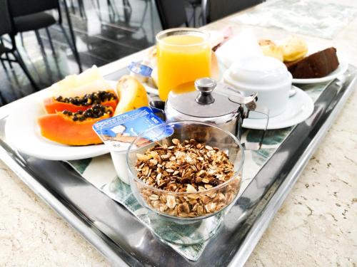a tray with breakfast foods and orange juice on a table at Savassi Village in Belo Horizonte