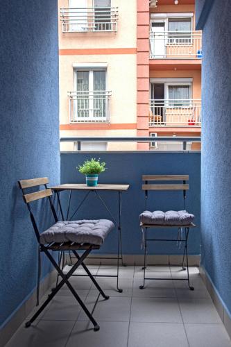 two chairs and a table on a balcony with a building at DK Apartment in Novi Sad