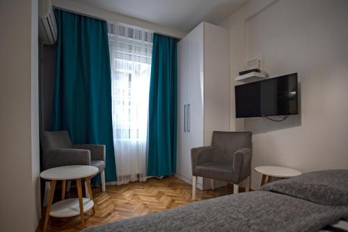 - une chambre avec un lit, deux chaises et une télévision dans l'établissement DK Apartment, à Novi Sad