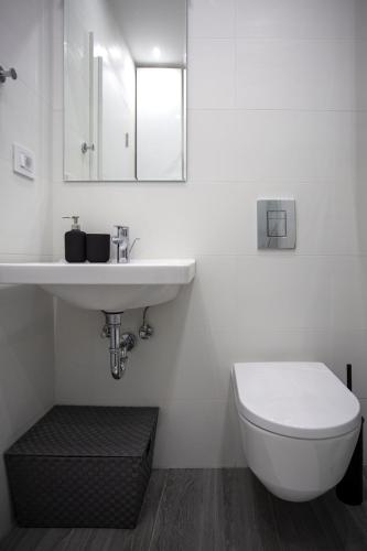 a white bathroom with a toilet and a sink at DK Apartment in Novi Sad
