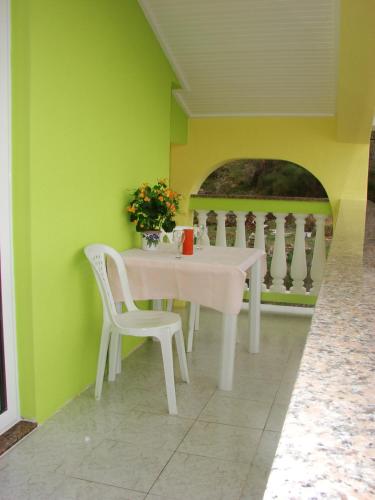 a white table and chairs in a room with green walls at Apartments Slavko in Supetarska Draga