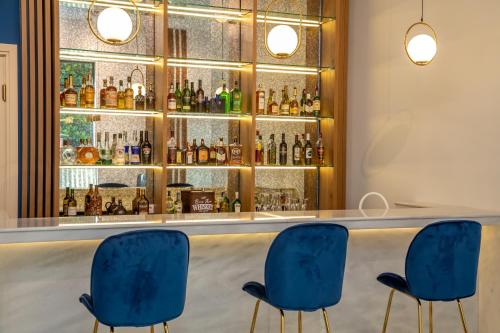 a bar with three blue chairs in front of a counter at Newport Hotel Kutaisi in Kutaisi