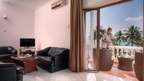 a man standing in a living room with a living room at Camelot Beach Hotel in Negombo