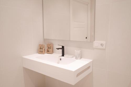 a white bathroom with a sink and a mirror at NUEVO Katu Kale Apartamentuak CENTRO HISTORICO in Getaria