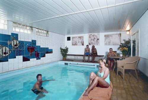 a man and a woman sitting in a swimming pool at Hotel Jägerhof in Staatsbad Brückenau